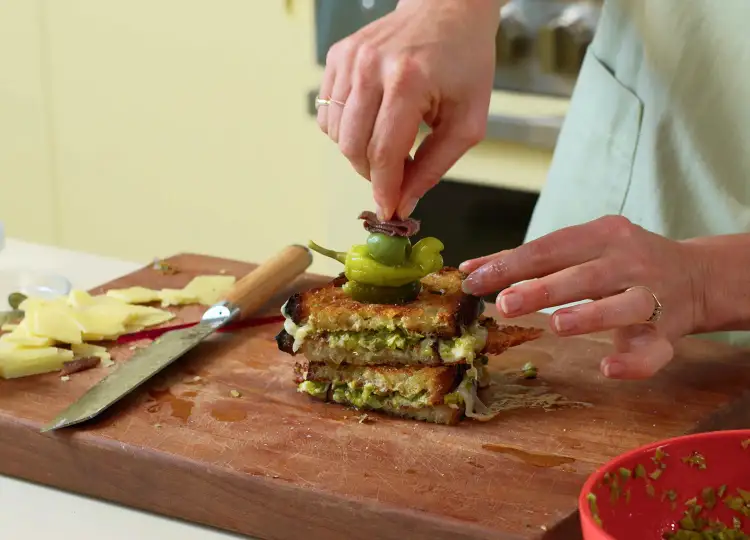 Molly Baz finishes up her Gilda Grilled Cheese with a skewer on top.
