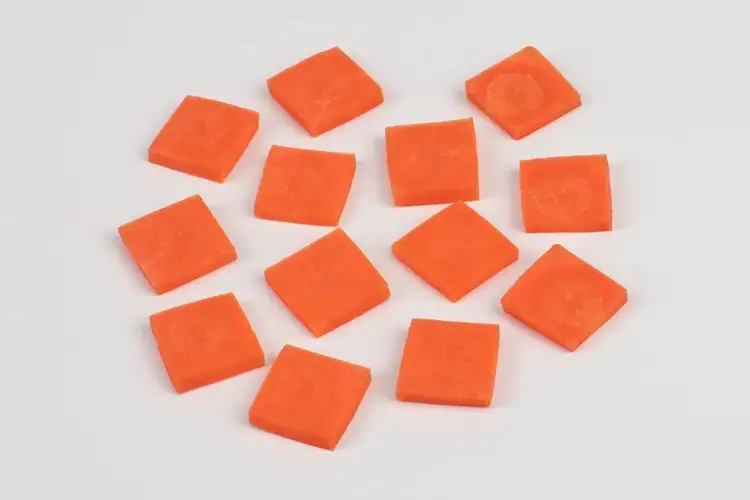 Carrots sliced into thin square pieces using the paysanne technique for quick cooking.
