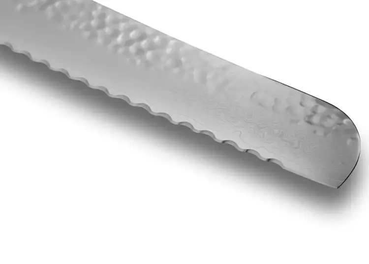 Blade detail of the Premier Bread Knife featuring wide, low-frequency serrations and Damascus layering.