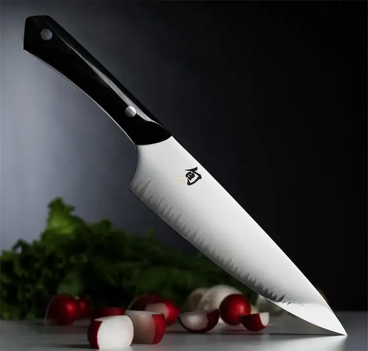A Narukami Chef's Knife points downward diagonally toward a countertop. Click to shop the Narukami Chef's Knife.