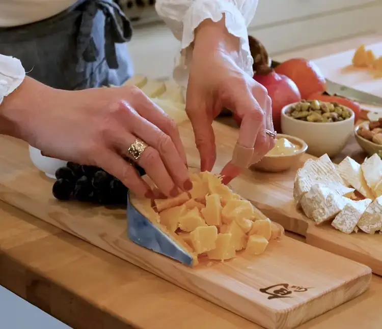 Arranging craggy chunks of aged cheese with rind acting as a border, next to a wedge of Camembert.