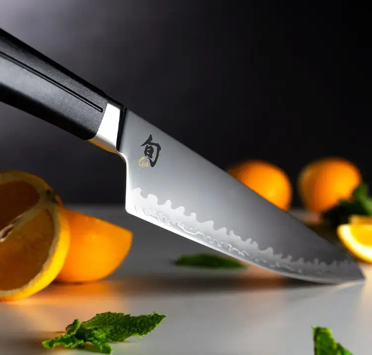 Angled view of Shun Sora Chef’s Knife next to orange slices and mint leaves, showcasing the cutting edge and precision detail of the blade.