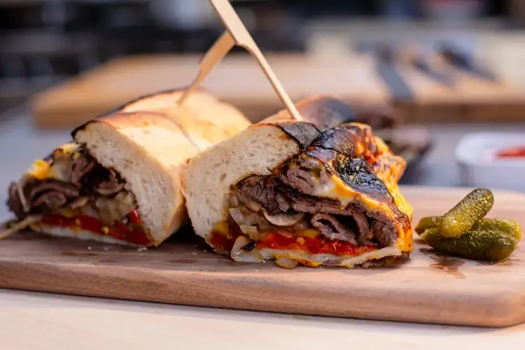 A grilled cheesesteak sandwich sliced in half.