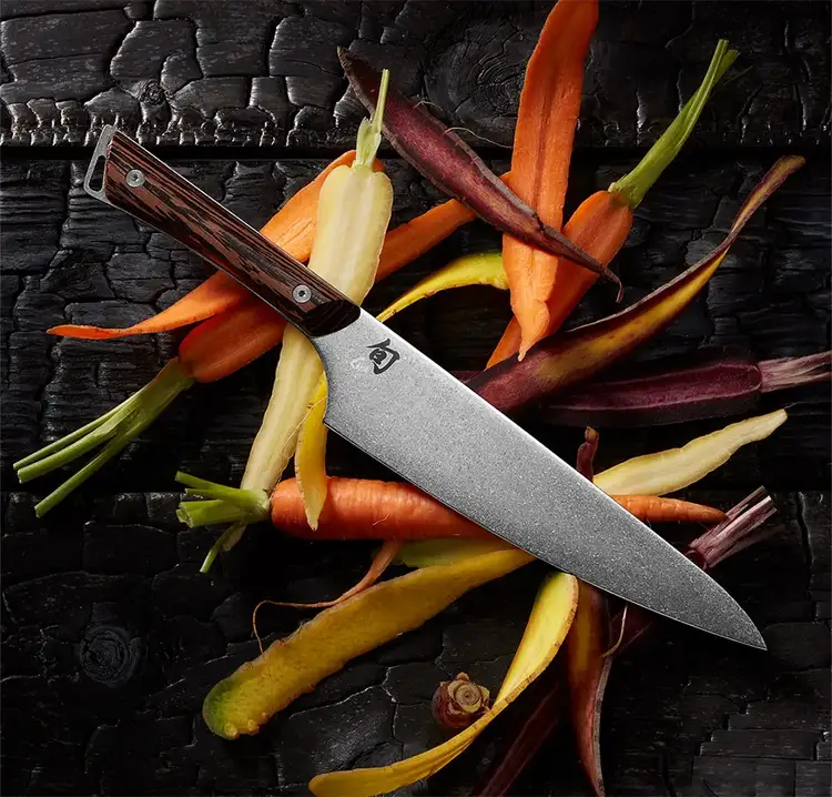 Shun Kanso 8-inch Chef’s Knife resting on a bed of colorful heirloom carrots. Click to shop the Kanso Chef's Knife.