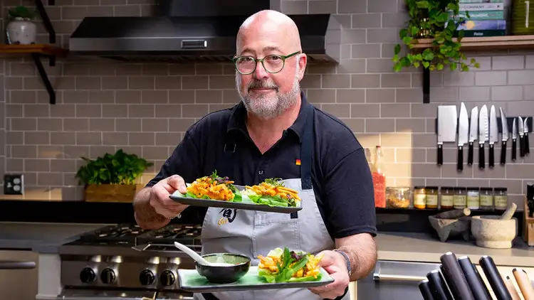 Chef Andrew Zimmern holding Vietnamese Sweet Potato and Shrimp Fritters on plates with dipping sauce