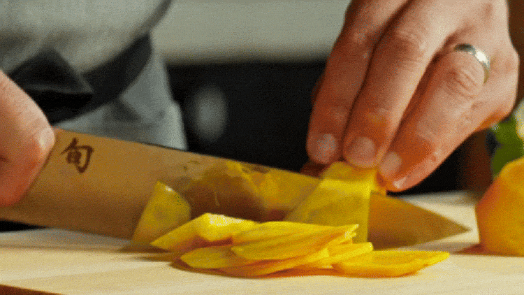 An video clip of the close up of a chef's knife slicing yellow beets.
