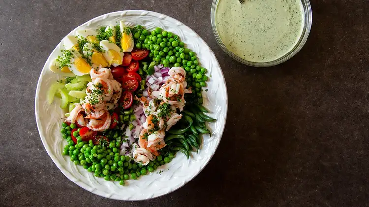 Steakhouse chopped salad in a bowl with a bowl of green dressing on the side