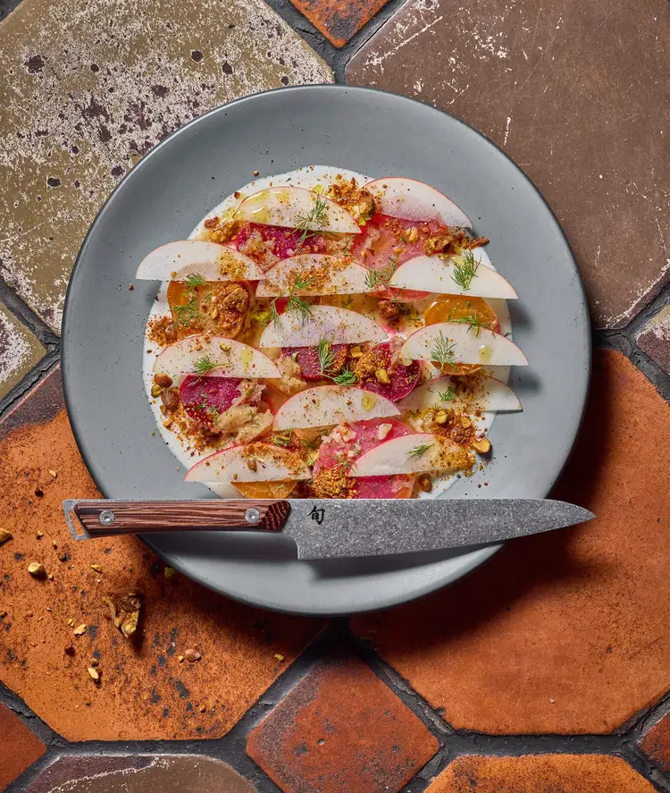 Apple, beet, and pistachio salad artfully layered and plated next to the Shun Kanso 6” Utility Knife.