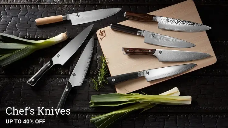 A grouping of Shun Chef's Knives lying on a table around a Hinoki cutting board.