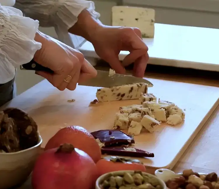 Slicing cranberry-flecked flavored cheese into bite-sized chunks with a Shun knife.