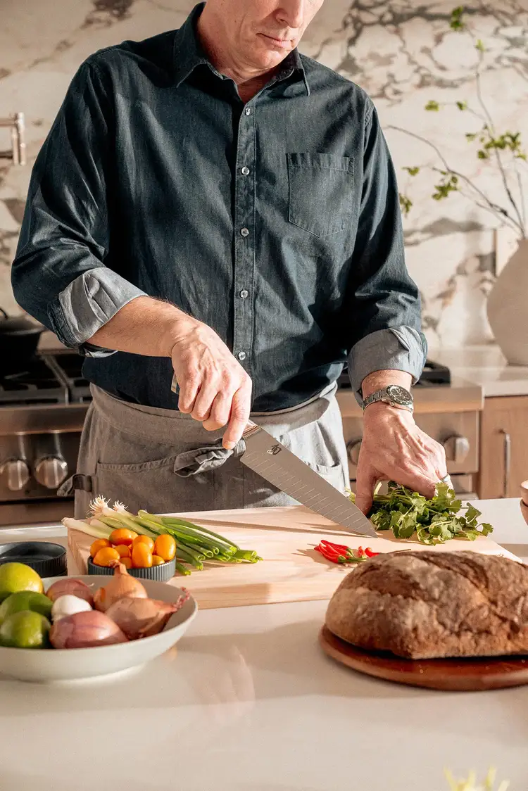 A chef stands in a kitchen, holding an authentic Shun knife.
