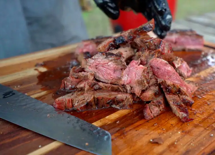Delicious slices of freshly grilled and sliced flank steak outdoors on a cutting board.