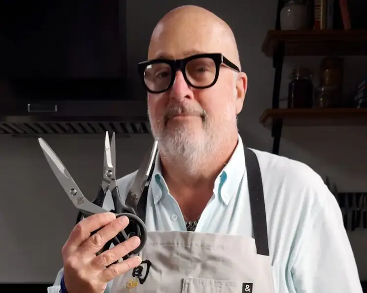 Andrew Zimmern holding Shun kitchen shears in a home kitchen.
