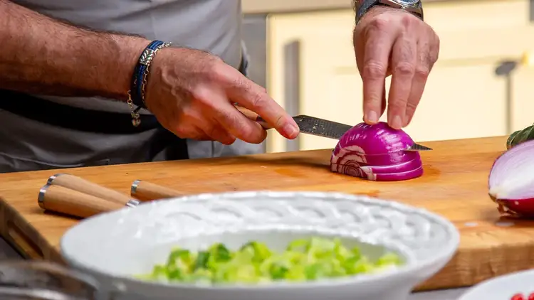 Chef Andrew Zimmern slicing a red onion for salad