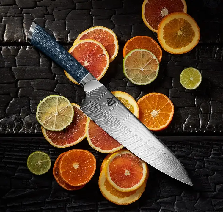 Shun Shiranami knife displayed with sliced citrus, showcasing the Damascus blade pattern and refined blade profile.