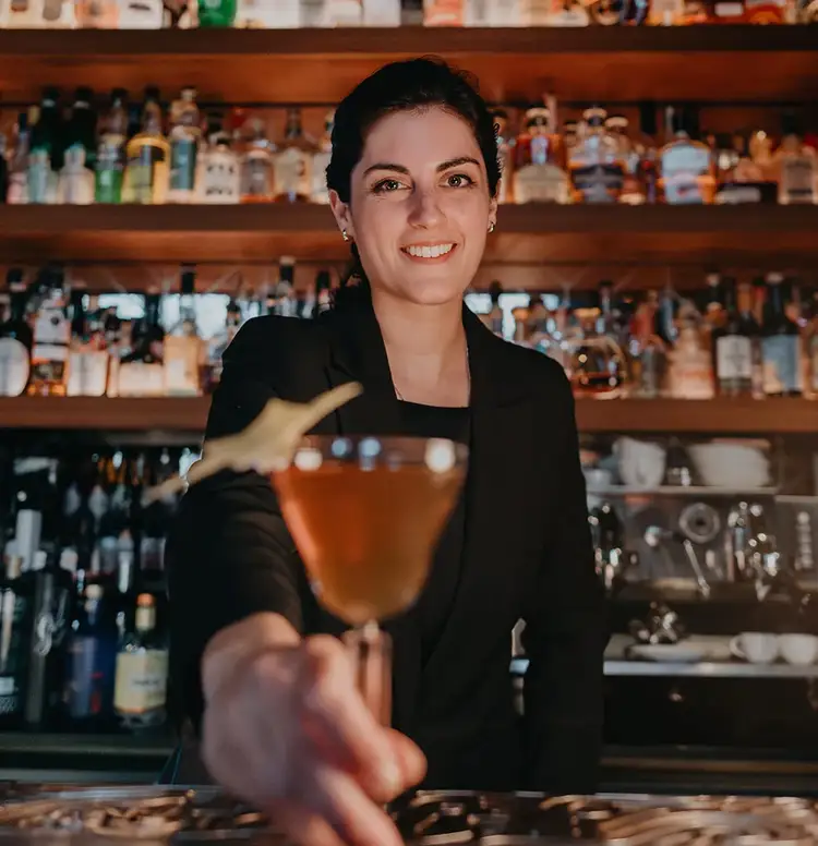 Bartender Gabriela Holzer holds a cocktail to the camera. Click to read her interview.