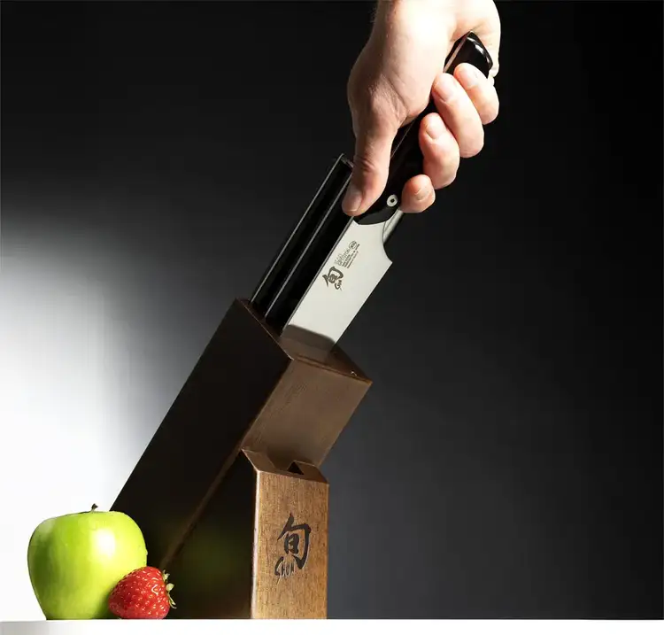 Hand placing Kazahana knife into a wooden Shun block—illustrating everyday usability, elegance, and long-term craftsmanship.