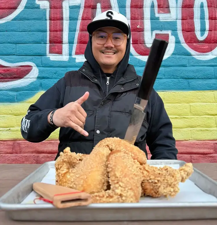 Chef Paolo Campbell stands in front of a plate of fried chicken. Click to read his interview.