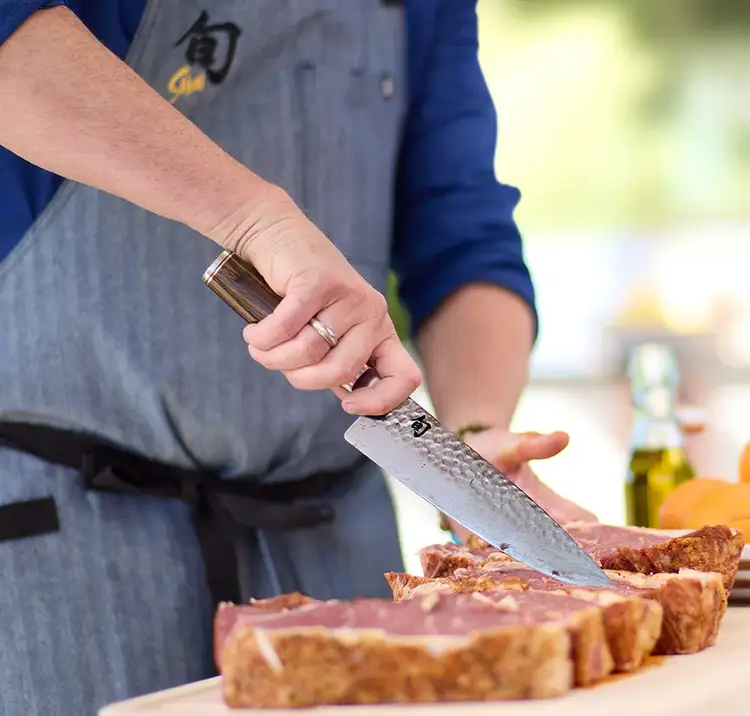 A chef slices a steak with a Premier Chef's Knife.