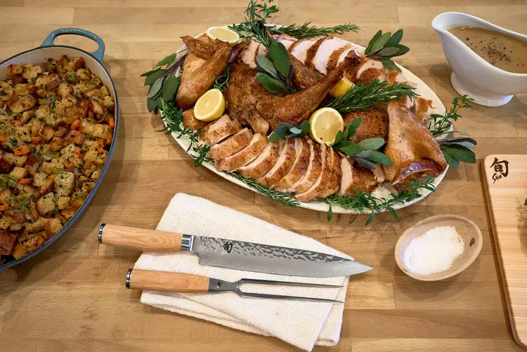 Garnishing carved turkey with fresh herbs and lemon for a holiday platter presentation.
