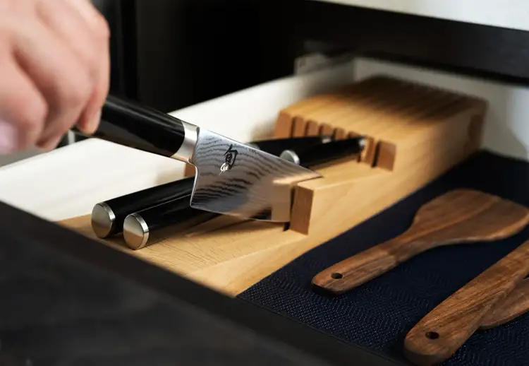 A knife is shown being taken out of an in-drawer knife tray.