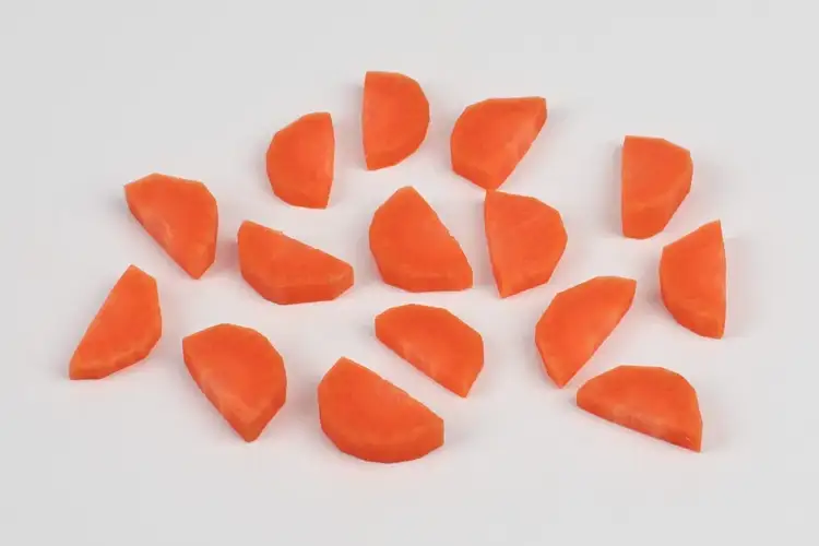 Carrots sliced into angled half-moons using the fermière cut, showing natural variation in shape and size.