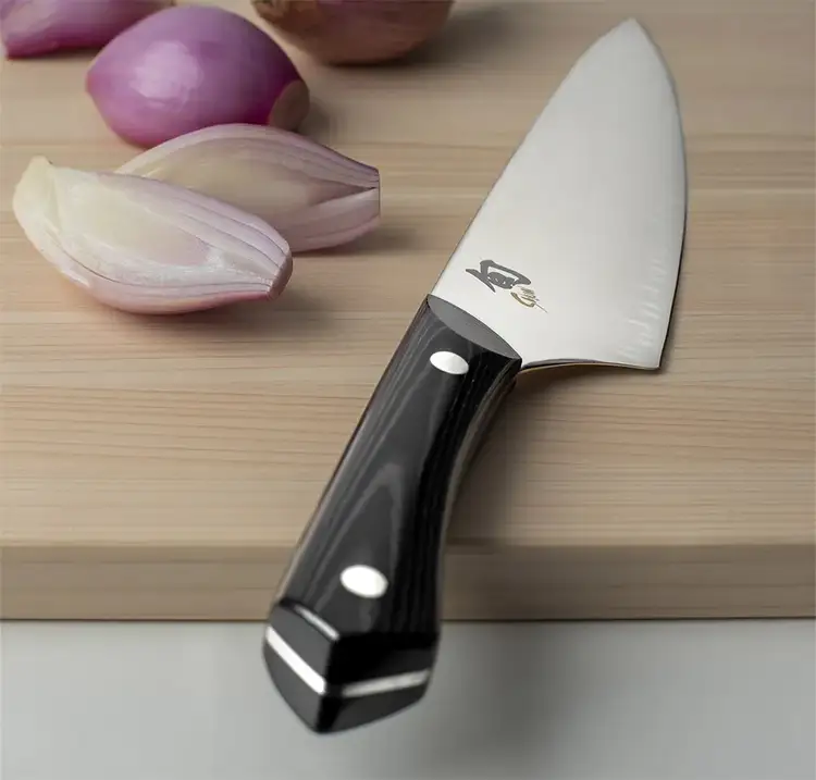 A Narukami Chef's Knife lies across a cutting board with the handle pointed towards the camera.