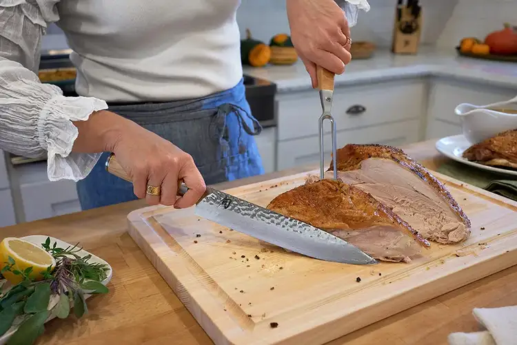Carving turkey breast away from the ribcage using the Shun Premier Blonde Carving Knife.