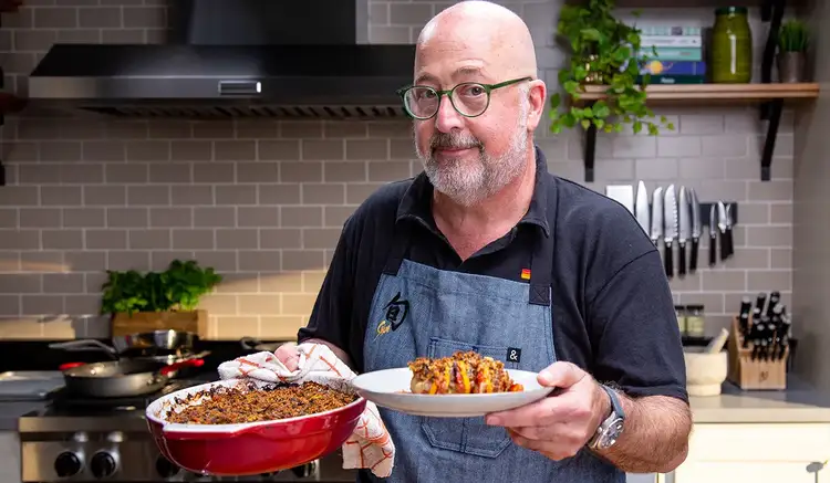 Chef Andrew Zimmern holding Vegetable Tian on a plate