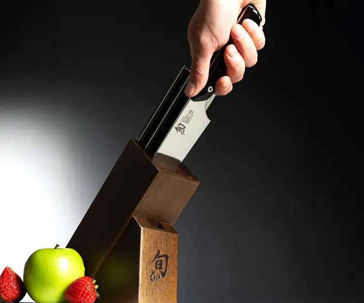 Shun knife being removed spine-first from a wooden knife block, demonstrating safe storage and proper handling.