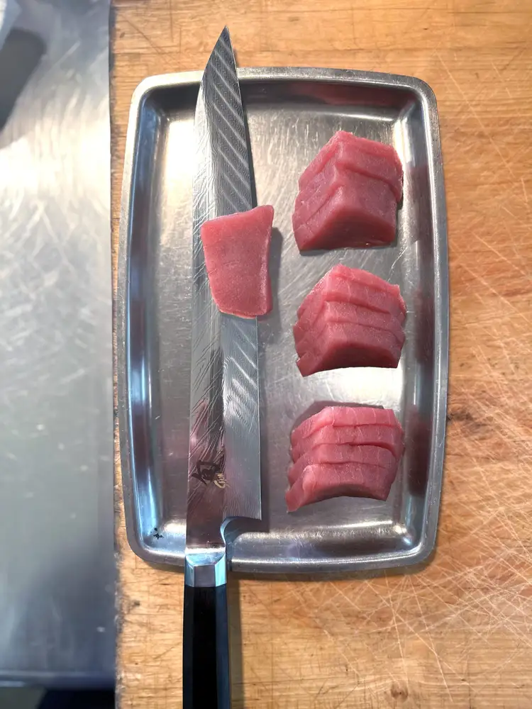 A Dual Core Yanagiba sits next to sliced fish.