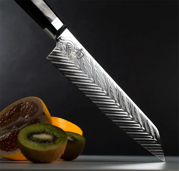 A Dual Core Kiritsuke points downwards on a tabletop, next to kiwi and citrus fruit. Click to shop the Dual Core Kiritsuke.