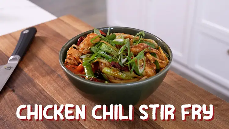Chili crisp chicken in a bowl with sliced scallions on top