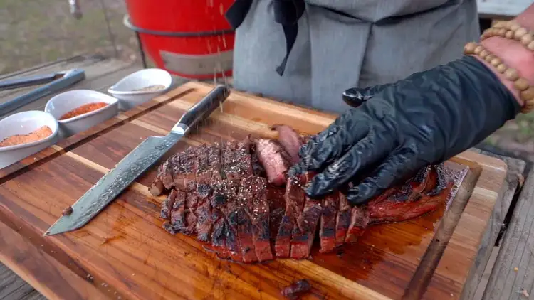 Sprinkling seasoning on perfectly grilled flank steak.