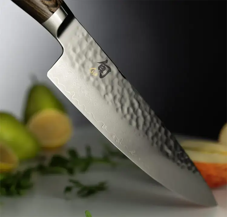 A Premier Chef's knife points downwards on a table.