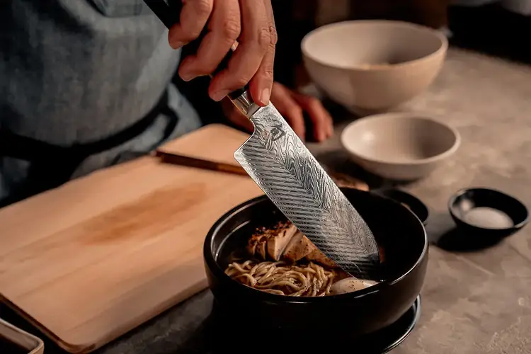 Chef Kim dips a Dual Core Santoku into a bowl of ramen.