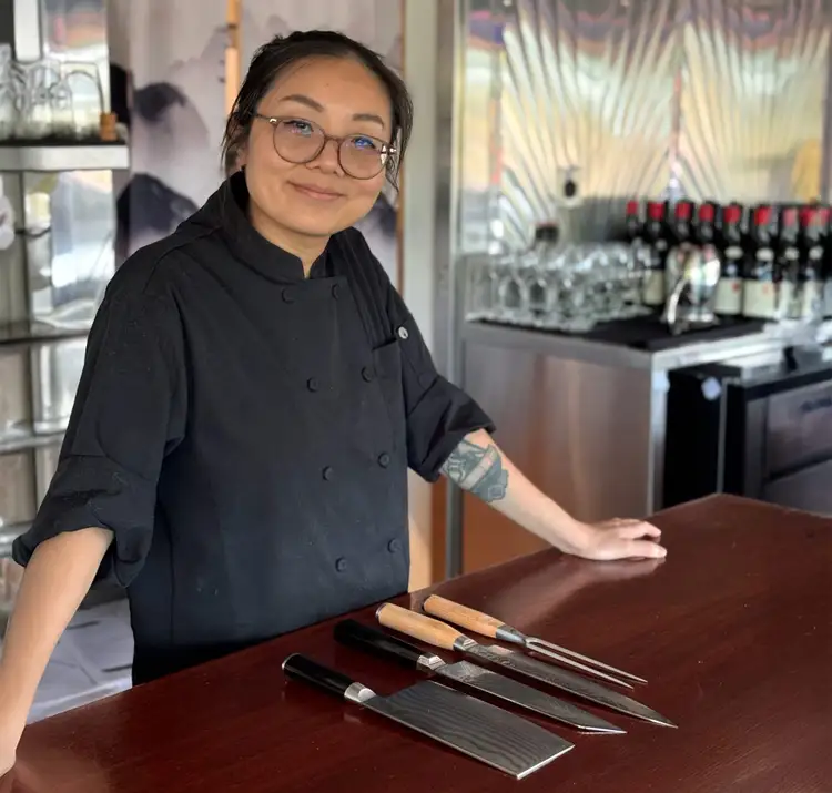 Chef Liu Fang stands behind the counter in her restaurant.