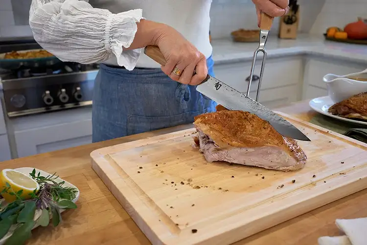 Carving turkey breast away from the ribcage using the Shun Premier Blonde Carving Knife.