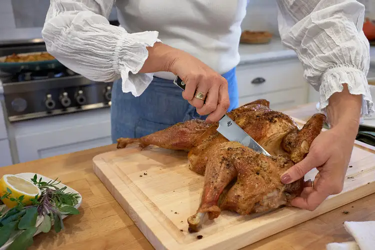 Removing a turkey leg using the Shun Kazahana Utility Knife after roasting.