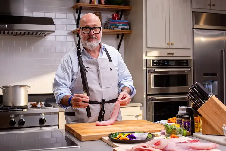 Chef Zimmern holds a freshly cut fillet of fish.