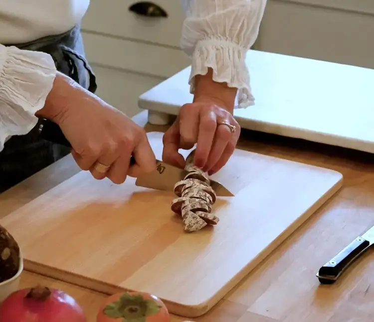 Using a Shun knife to slice hard salami on a cutting board for the cheeseboard.