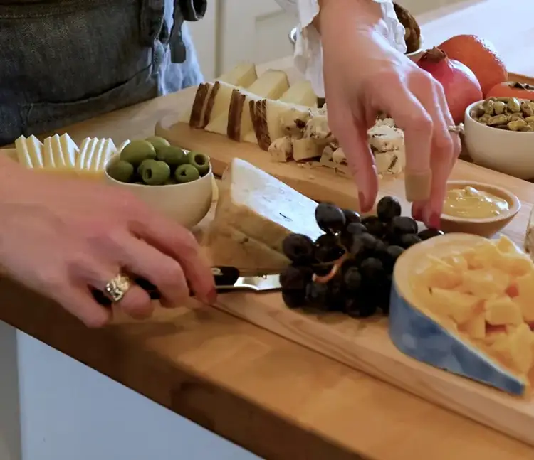 Tucking grapes between wedges of cheese with a Shun knife resting on the board, adding the final touches.